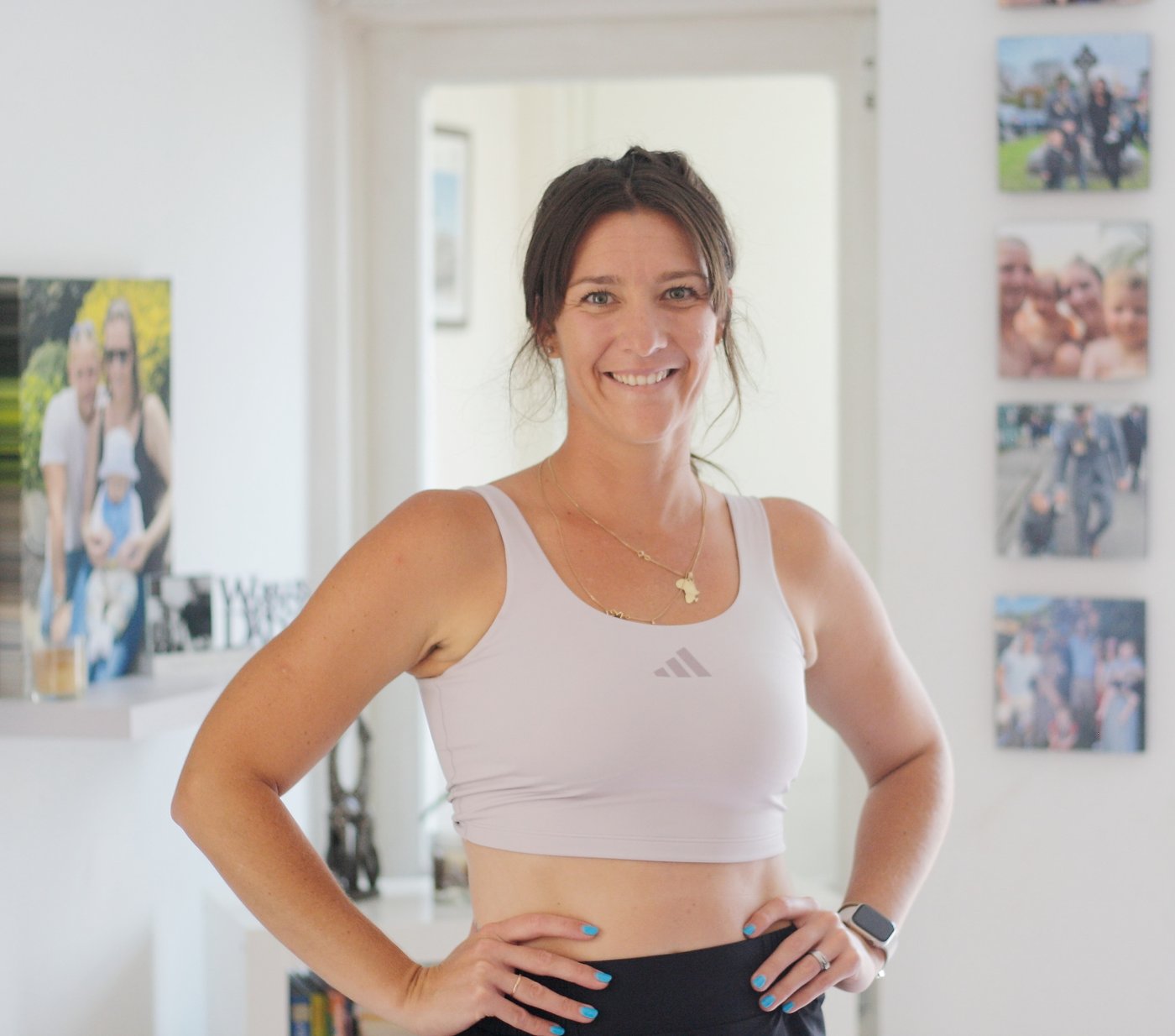 Laura smiling with her hands on her hips, wearing a lilac sports bra